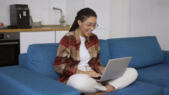 Positive Girl with Dreadlocks is Laughing and Smiling with Laptop on Knees