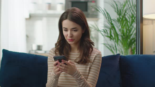 Attractive Happy Young Woman is Using Smart Phone at Home Getting Good News