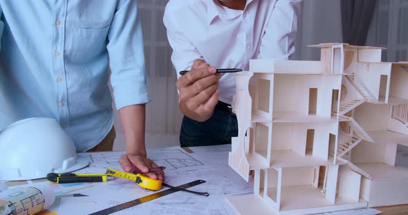 Two Male Architects In Office Discussing Construction Project