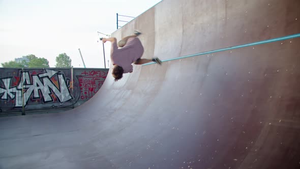a Freerunner in a Skate Park Against the Background of Graffiti Making an Acrobatic Bunch of