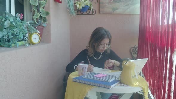 Busy Businesswoman In A Hurry Looks On Her Watch And Alarm Clock While Writing On The Table. medium