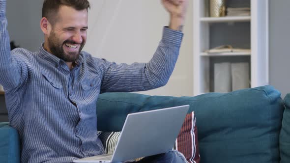 Man Excited for Success, Working on Laptop