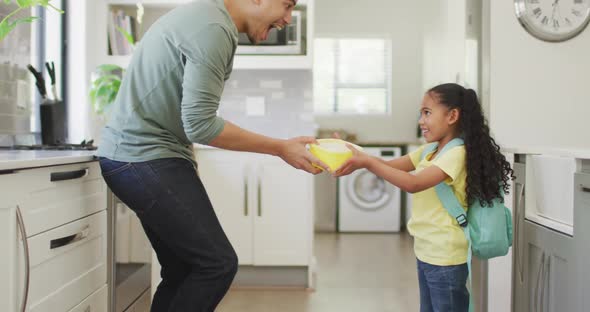 Happy biracial father and daughter embracing in kitchen