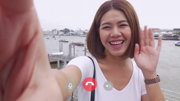 Beautiful Asian female taking selfie video chat with her friends.