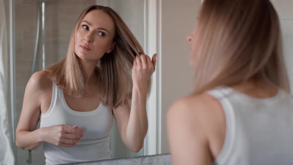 Caucasian woman checking hair condition in the bathroom. Shot with RED helium camera in 8K.