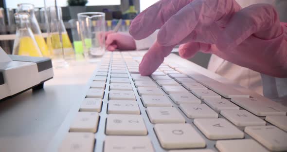 Scientist Typing on Laptop Table and Making Notes in Card While Working Closeup