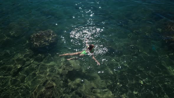 Slowmotion Top View Sexy Slim Woman with Nise Buttocks in Green Swimsuit Floating in Clear Turquoise