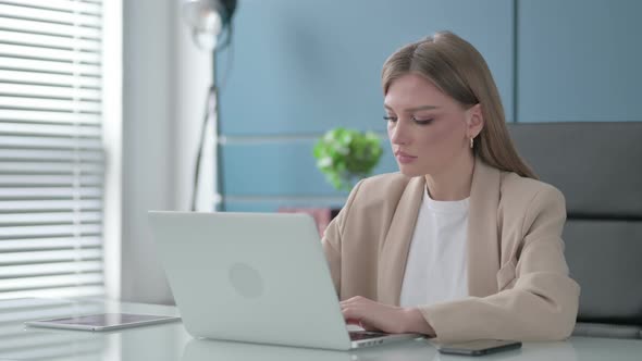 Businesswoman Looking at Camera While Using Laptop in Office