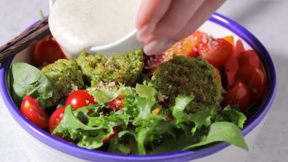 Cooking and eating falafel salad with tahini dressing and vegetables. 