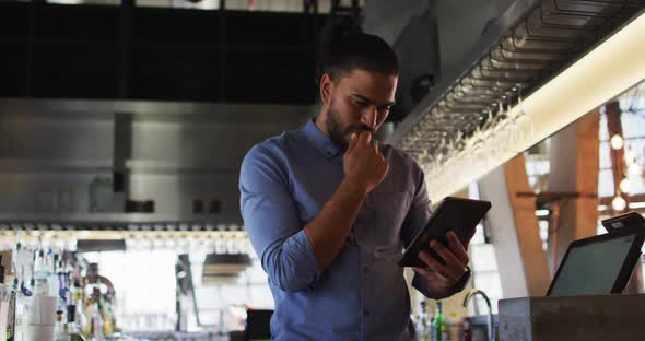 Portrait of mixed race male cafe owner using tablet and looking to camera