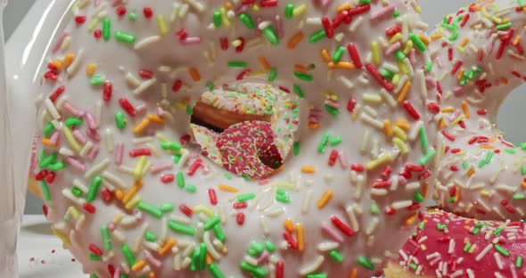 Multi colored donuts with sprinkles. Table with donuts and coffee.