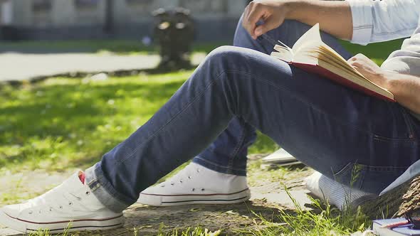 Teenager Enthusiastically Reading Book Sitting Outdoors and Breathing Fresh Air