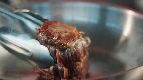 Close-up of a raw filet mignon being cooked in a frying pan