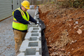 Construction worker is mounting a retaining wall using concrete blocks to ensure its proper - PhotoDune Item for Sale