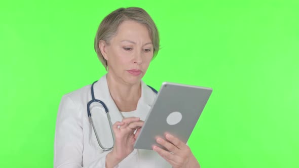 Old Female Doctor Using Digital Tablet on Green Background