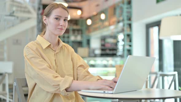 Laptop Use By Young Woman Smiling at Camera in Cafe 