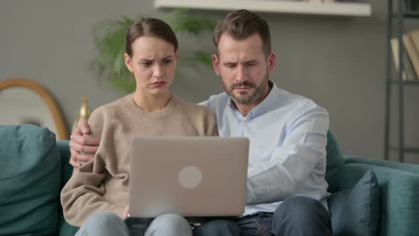 Couple Reacting to Loss on Laptop While Sitting on Sofa