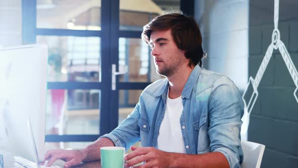 Man having coffee while working on computer