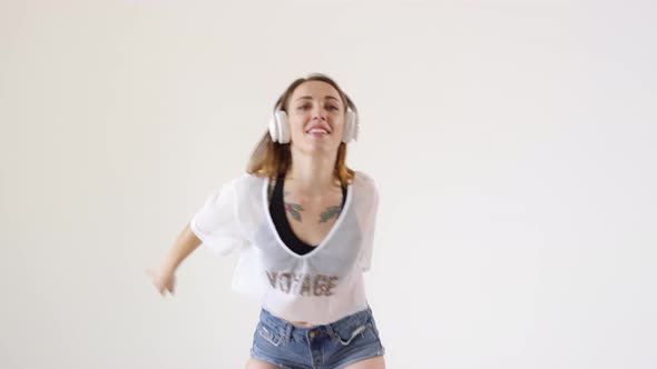 Young Happy Woman in Wireless Headphones Dancing in Studio