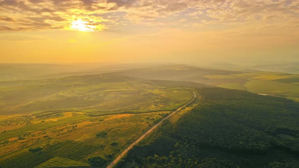 Aerial drone view of nature in Moldova at sunset. Highway, wide fields and hills, forest