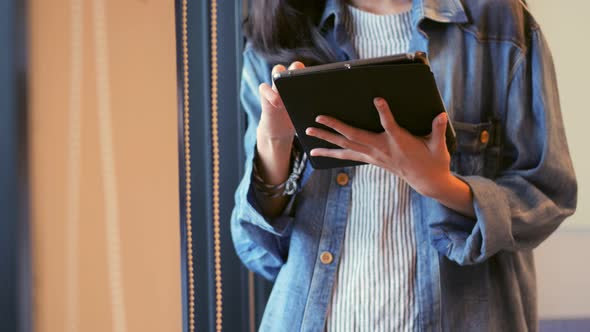 Young beautiful Asian woman using tablet beside a window at the office.