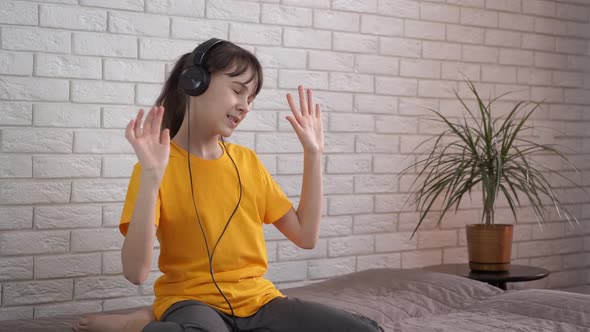 Child in happy dance in headphones.