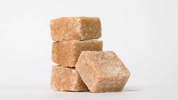 Pieces of brown unrefined sugar rotating on white background