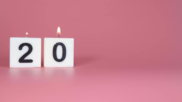 A square candle saying the number 20 being lit and blown out