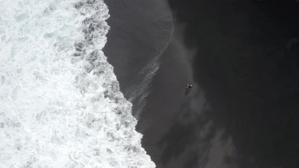 Aerial view of a person standing at Black Sand Beach, Reunion Island.