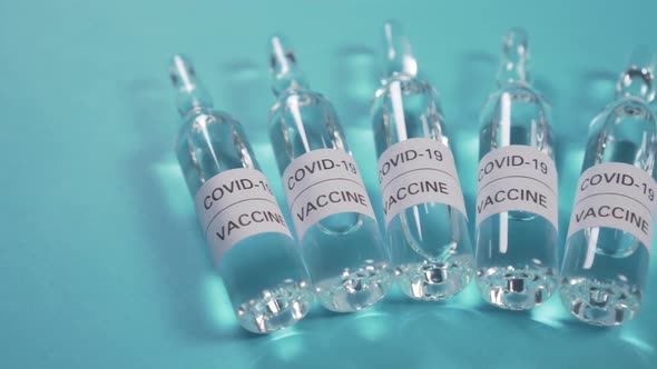 Five ampoules with a coronavirus vaccine on a blue background. 