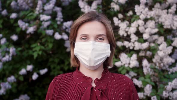 Close up portrait of caucasian beautiful young woman in medical mask standing outdoor. Healthcare.