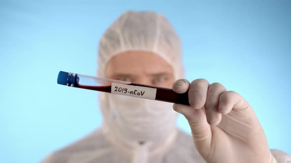 Man in protective suit, medical mask, gloves shows test tube with Coronovirus alt