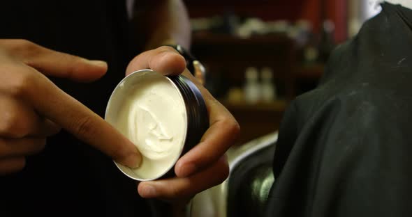 Barber taking out hair wax from wax can at barber shop 