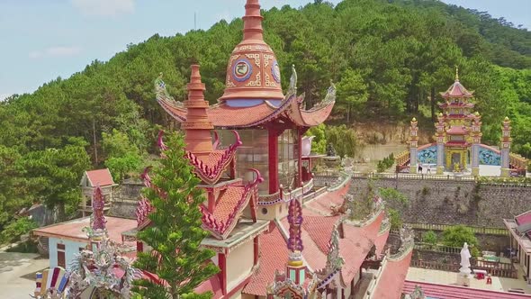 Flycam Shows Red Fretted Pagoda Roof Among Buildings Plants