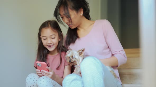 Positive Asian mom and daughter looking at phone