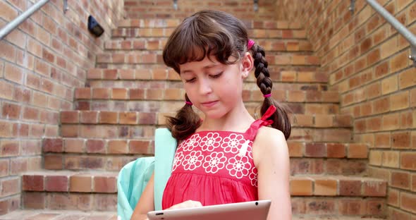 Schoolgirl using digital tablet at staircase in school