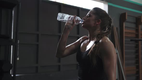 Sporty Beautiful Woman Eagerly Drinking Water From a Bottle After Training in the Gym