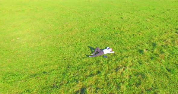 Low Orbital Flight Around Man on Green Grass with Notebook Pad at Yellow Rural Field.