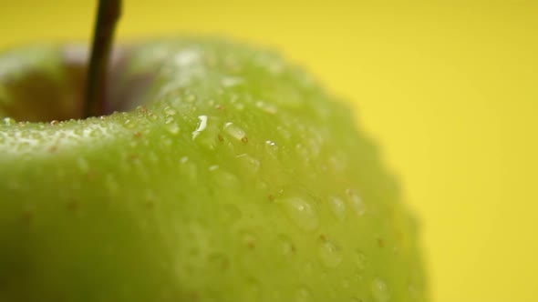 Water drops close-up on a green apple. Spraying fresh fruit in slow motion