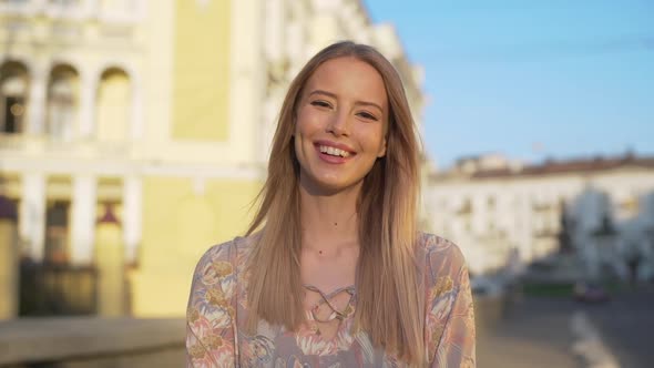 Portrait of European Joyous Woman 20s with Blond Hair Wearing Dress Laughing While Strolling Through