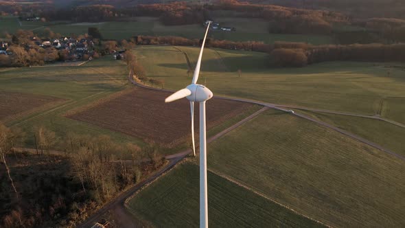 Large, white wind turbine in North Rhine Westphalia, Germany during a sunset in winter. Aerial close