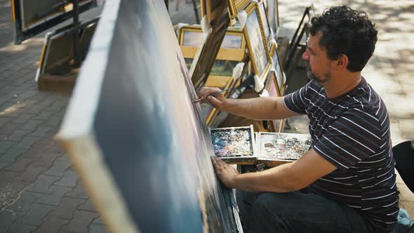 Gifted Man Artist Drawing Picture with Marine Landscape and Sailing Ships While Sitting in Park