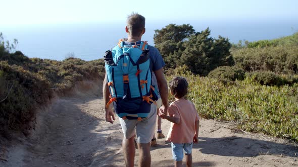 Family of Hikers with Backpacks Walking on Path Outdoors