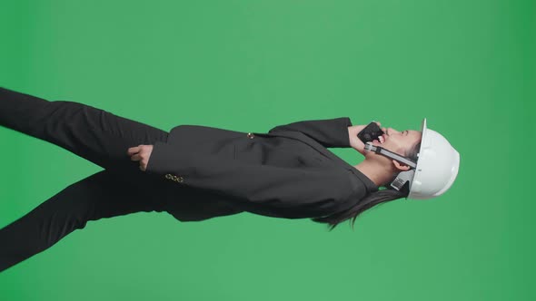 Side View Of Female Engineer Talking On Smartphone And Celebrating While Walking On Green Screen