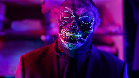 a Man in a Terrible Glowing Mask of Death Lets Out Clouds of Smoke From Under It in a Neon Flashing