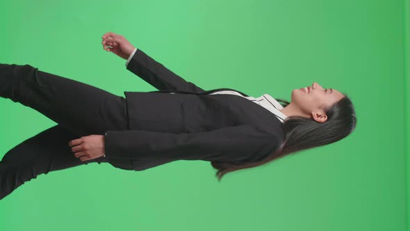 Side View Of A Smiling Asian Business Woman Walking Through Green Screen In The Studio