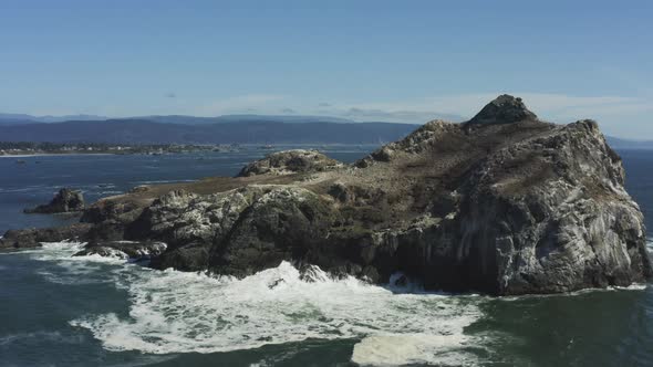 Powerful aerial drone footage, slowly approaching a very large Pacific ocean boulder which is surrou