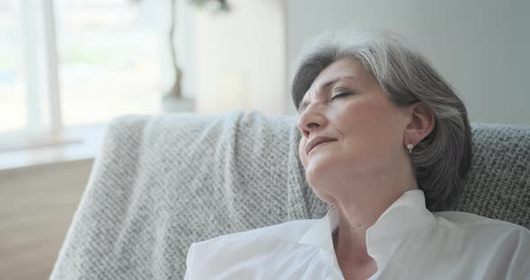 An Elderly Woman is Snoozing in a Comfortable Chair Relaxing and Resting Her Energy