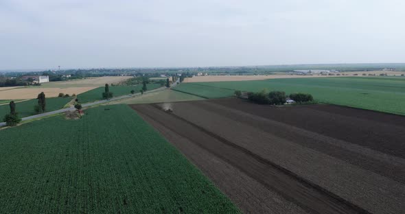 Tractor Tilling Soil Surrounded By Corn And Wheat Crops In The Field