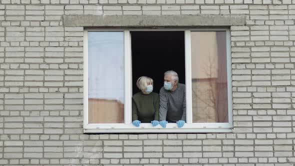 Old Grandparents Stay at Window Isolated at Home on Quarantine. Coronavirus